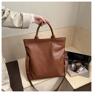 Brown faux leather tote bag with adjustable strap in a stylish office commuter setting