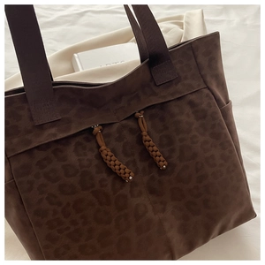 Detail of dark coffee leopard print tote bag with thick shoulder strap and woven zipper pull