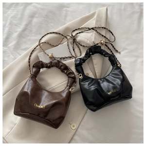 Detail of ruched croissant bags in black and coffee with gold chain shoulder straps