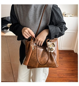Close-up of retro brown faux leather tote bag with a matching pouch and cute bear pendant