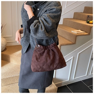 Detail einer dunkelbraunen gesteppten Wildleder-Schultertasche mit Kettenriemen