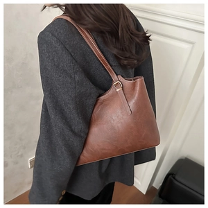 Détail du sac cabas marron vintage avec coutures contrastées blanches et boucle dorée