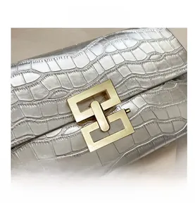 Macro shot of silver crocodile embossed texture and golden geometric interlocking metal buckle