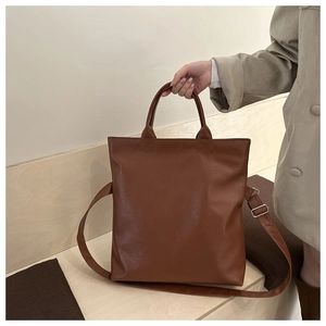 Close-up of brown faux leather tote bag showing fine texture and circular handles