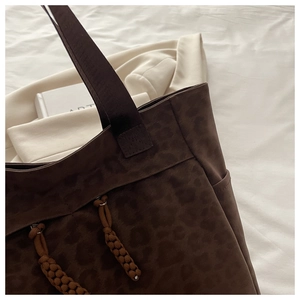 Macro detail of dark coffee leopard tote bag with woven ropes and suede texture