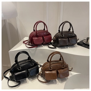Minimalist Boston handbags in four colors displayed on white stands with gold lettering