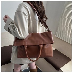 Detailed view of brown lychee-patterned leather tote bag worn by a model in soft light
