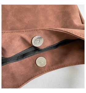 Detailed close-up of brown suede shoulder bag featuring secure magnetic clasp closure