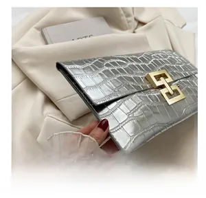 Close-up of metallic silver crocodile embossed envelope clutch with golden buckle