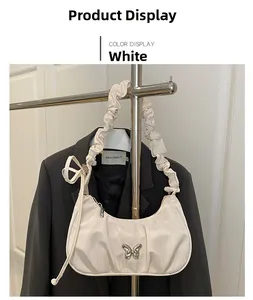 Detail of white ruched shoulder bag with silver butterfly charm and drawstring strap