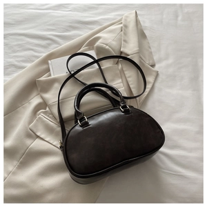 Detail of deep brown bowling bag with gold hardware and slim shoulder strap