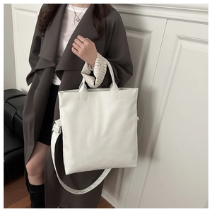 Detailed side view of the white textured leather tote bag on model's shoulder