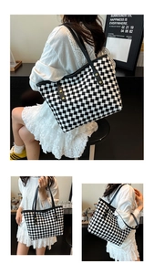 Close-up of black and white checkered tote bag with leather handles and gold rivets