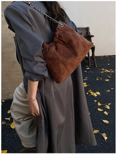 Detail einer braunen Wildleder-Schultertasche mit Rautensteppung und Metallkettenriemen