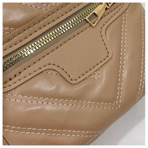 Close-up of premium brown leather bag showing golden metal zipper and dual stitching