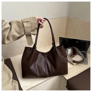 Detail view of large dark brown leather tote bag showing smooth texture and long handles
