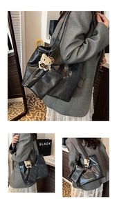 Close-up of black leather tote bag with a small zipper pouch and a plush cat charm
