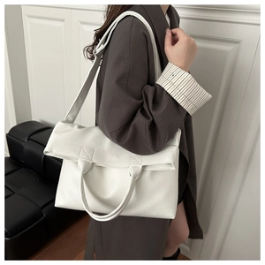 Detailed shot of a white lychee grain leather tote bag worn by a model in a modern room