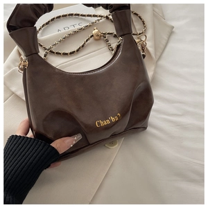 Detailed macro of dark brown ruched handbag with gold chain strap and brand logo