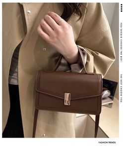 Detailed view of deep brown vintage handbag featuring a metallic buckle and textured leather