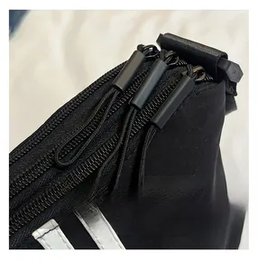 Dettaglio borsa in nylon nero con tre cerniere e strisce laterali bianche a contrasto