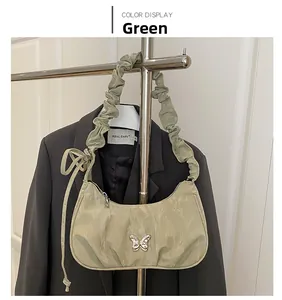 Detail of light green pleated shoulder bag featuring a silver butterfly buckle and silk texture