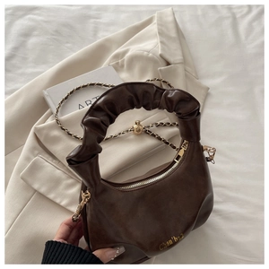 Detail of caramel brown leather dumpling bag with ruched handle and gold chain strap