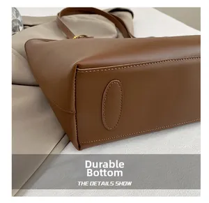 Detail shot of a brown leather tote bag showing a reinforced wear-resistant base and stitching