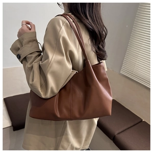 Detailed side view of the large brown leather tote bag worn with a beige trench coat