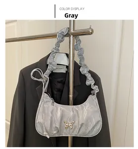 Detail of silver pleated shoulder bag with golden butterfly on a black blazer