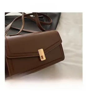 Detailed view of dark brown leather crossbody bag with stitching and gold turn-lock