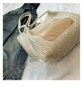 Détail d'un sac cabas en paille tissée avec empiècement en cuir et anses en corde