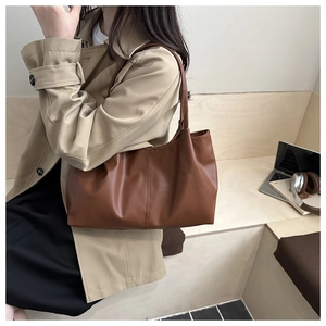 Detailansicht der braunen Leder-Tote-Bag mit Plissee-Design vor Stadtkulisse