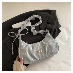 Detail of silver pleated crescent bag with metal butterfly buckle on a black blazer