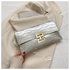 Silver envelope clutch bag with crocodile pattern and golden buckle on blazer background
