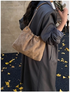 Braune Wildleder-Schultertasche mit Rautensteppung und Kette über grauem Mantel getragen