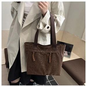 Détail d'un grand sac cabas léopard marron avec des glands tressés et texture suédine