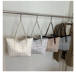 Detail of four checkered tweed tote bags in white, grey, brown and black with leather straps