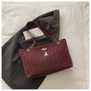 Dettaglio della borsa tote leopardata bordeaux con catena dorata e ciondolo a cervo