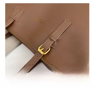 Detail of premium brown leather tote showing fine stitching and gold metal buckle