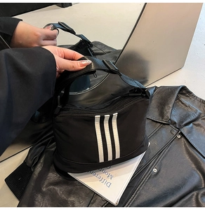 Dettaglio della borsa a tracolla sportiva in tessuto nero con tre strisce bianche verticali