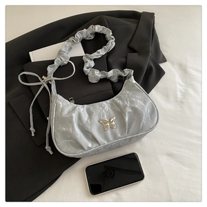 Detail of silver butterfly buckle and pleated texture on light grey shoulder bag