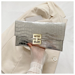 Close-up of silver crocodile embossed envelope clutch bag with gold interlocking buckle