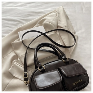 Detail of dark brown leather bowling bag with front pockets and gold fashion text