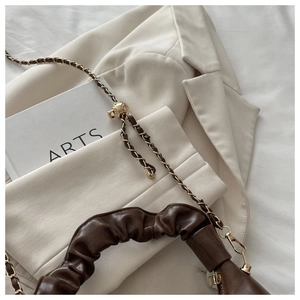 Detail of brown pleated leather bag with gold chain strap and metal adjustment ball