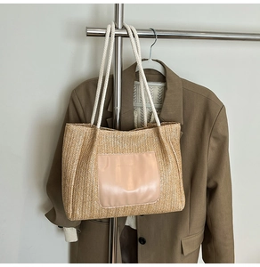 Détail d'un sac cabas en paille avec une poche en cuir rose et des poignées en corde