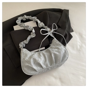 Detail of silver crescent bag featuring unique pleated texture and ruffled shoulder strap