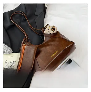 Detail of a large brown faux leather tote bag with a small pouch and character pendant