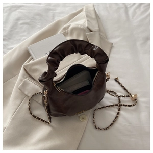 Detail view of brown glossy shoulder bag with pleated handle and golden chain strap
