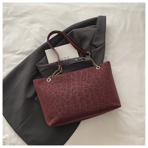 Borsa bordeaux con stampa leopardata e catena dorata su blazer grigio elegante